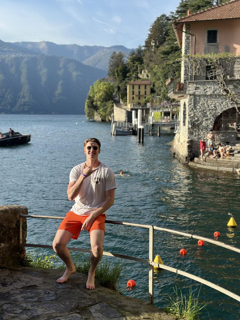 Andrew sits in front of a coastal view of houses and mountains