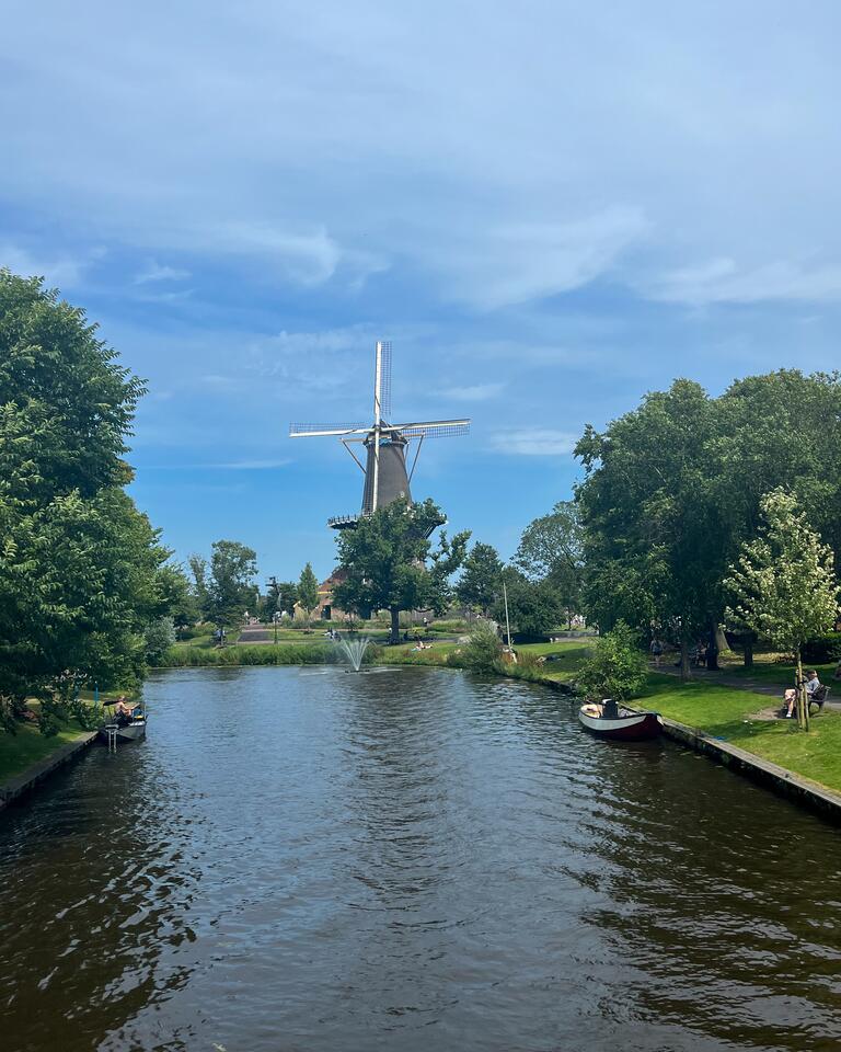 A small river with a windmill in the distance