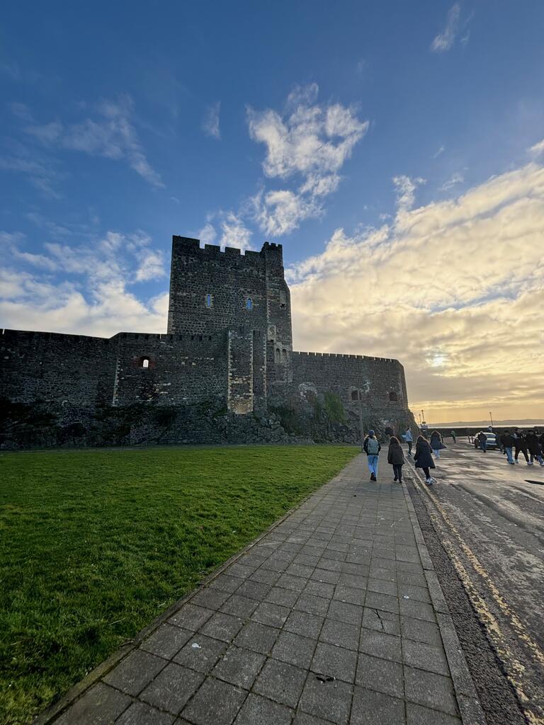 An old castle with a blue sky. People milling about in the distance