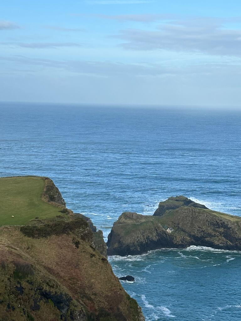 A green cliff in front of a vast body of water
