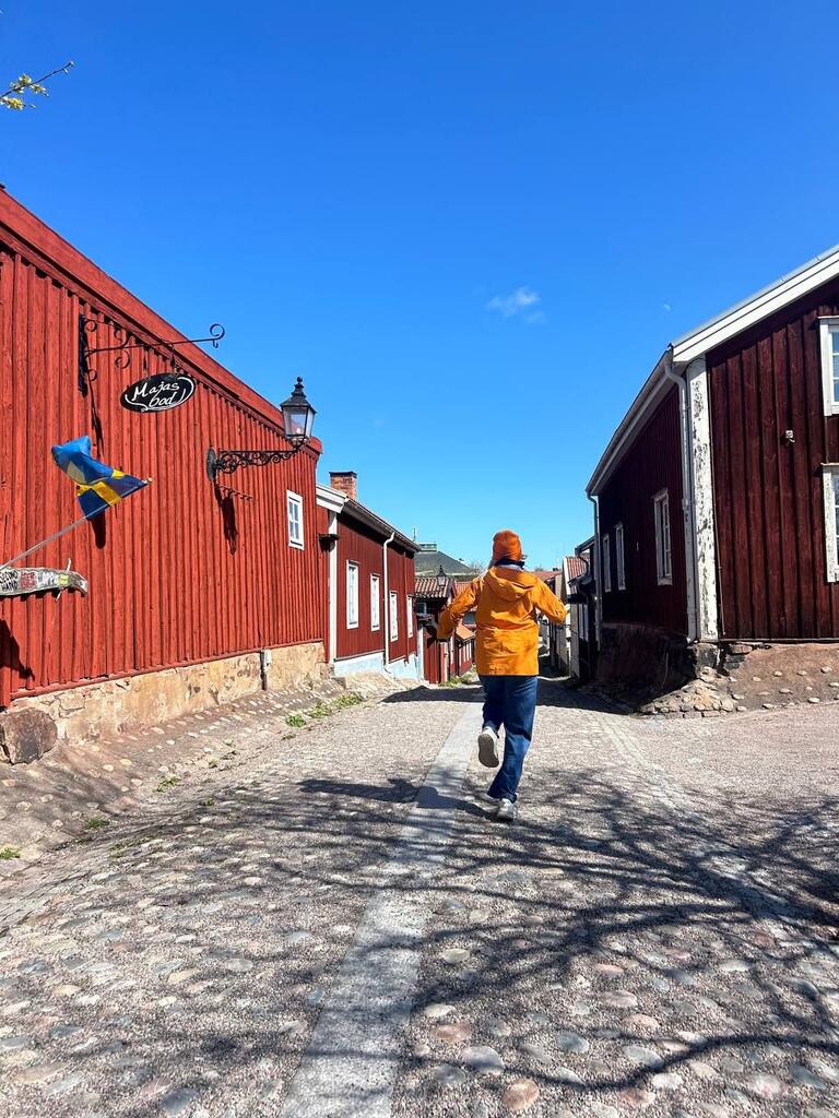 Solomiia is running a yellow jacket, with a blue sky, and red barns