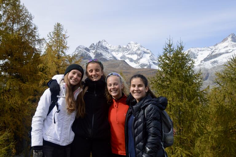 Alyssa and friends posed for a picture outside with trees and mountains in the background.