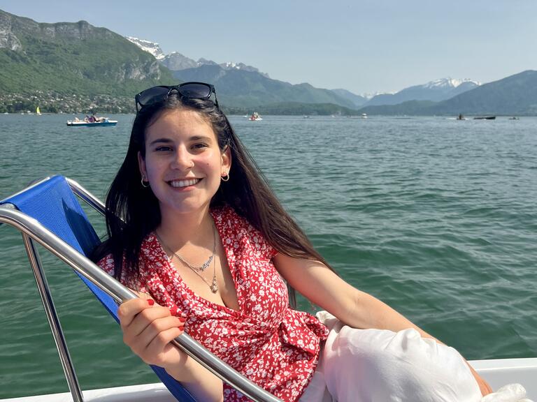 Alyssa posed comfortably on a lounge chair on a boat with water in the background. 