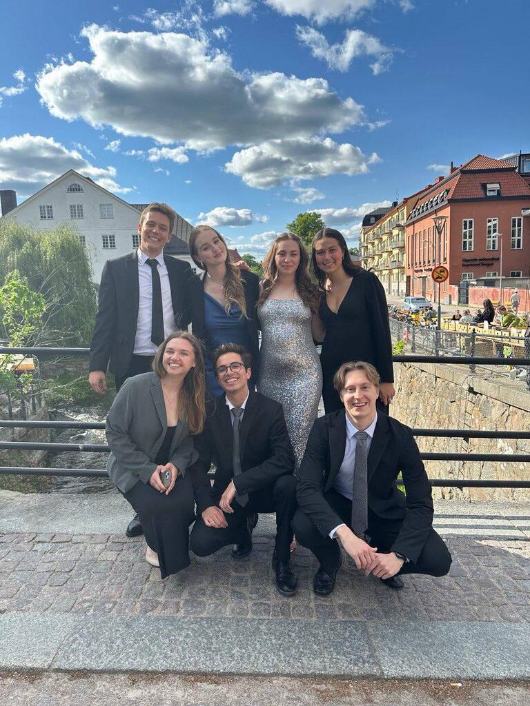 Solomiia and friends dressed up for an event on a bridge with blue sky and old buildings in the background