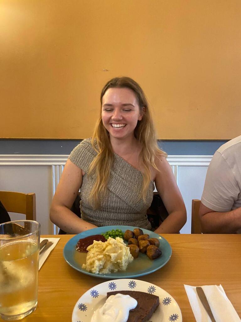 Solomiia smiles for the camera with a Swedish meatball meal on the table in front of her.