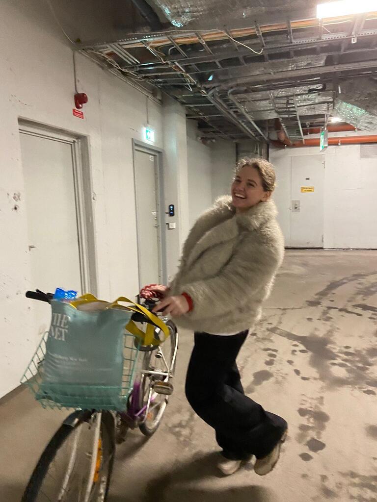 Solomiia poses with a bicycle in a furry jacket