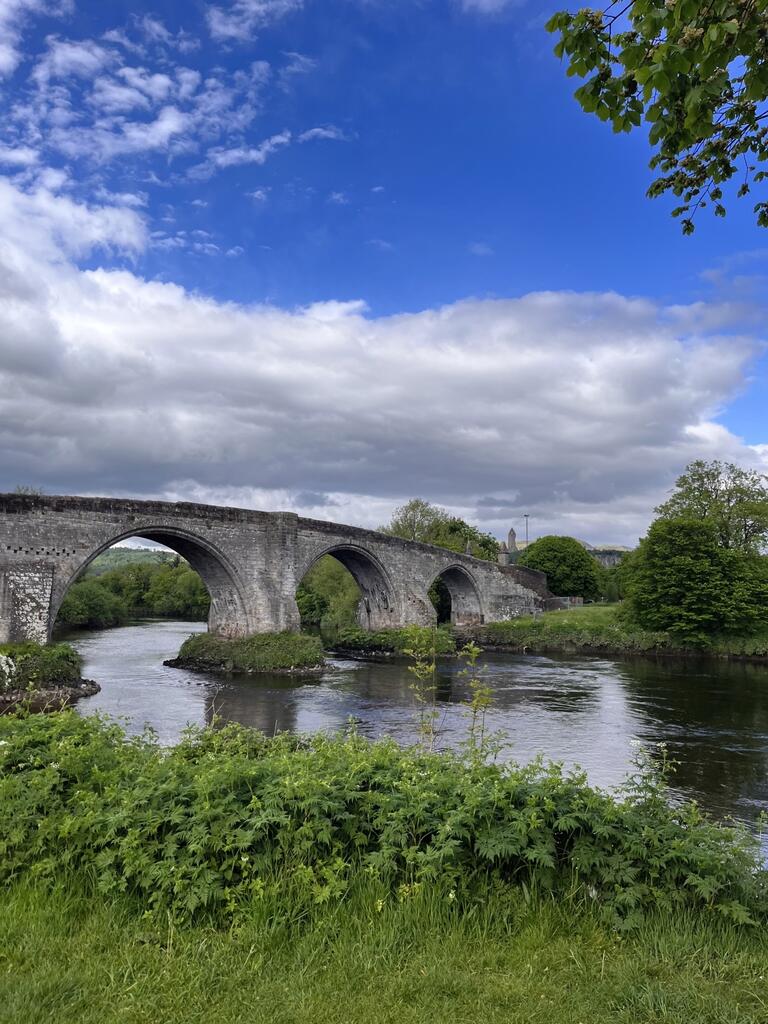 A bright sunny day with a historic stone bridge over a river
