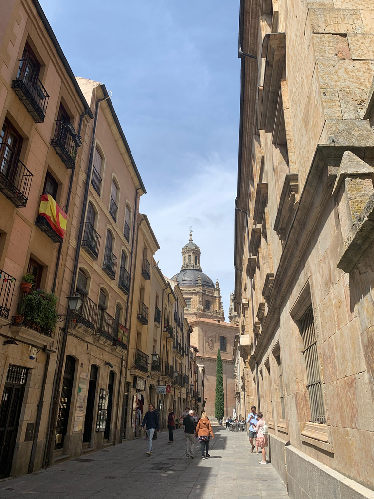 A historic street, a spanish flag, and a domed building in the distance