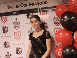 Patricia is posing in front of an event backdrop in formal wear