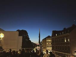 A city skyline taken from a rooftop bar at dusk