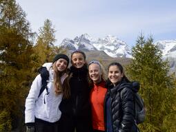 Alyssa and friends posed for a picture outside with trees and mountains in the background.