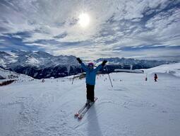 Alyssa skiing with arms outstretched to the sky.
