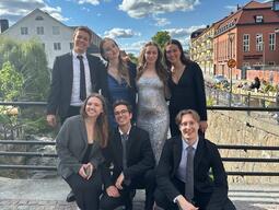 Solomiia and friends dressed up for an event on a bridge with blue sky and old buildings in the background