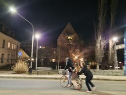A candid capture of two people riding a bicycle, and another pushing from behind