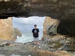 Student stands on a rock formation in front of a body of water