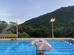 Swimming pool, colourful umbrella, and rolling hills in the distance