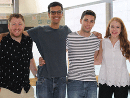 Five people standing with their arms around each others shoulders