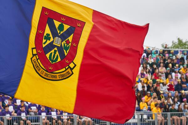 Queen's tricolour flag in front of a crowd of students during Orientation