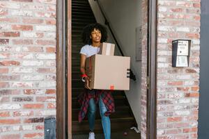 A tenant walking out of her building carrying a box