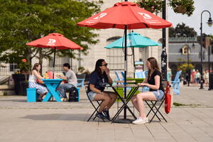 people sitting at bistro tables enjoying the outdoors, downtown Kingston. 
