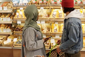 two people grocery shopping and looking at bread options.