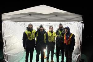 Stratotegic team under a tent canopy at night
