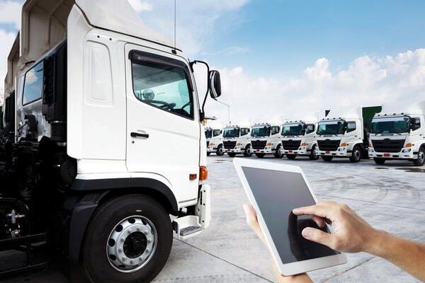 A row of trucks ready for deployment. A hand in the foreground is pointing at a tablet screen