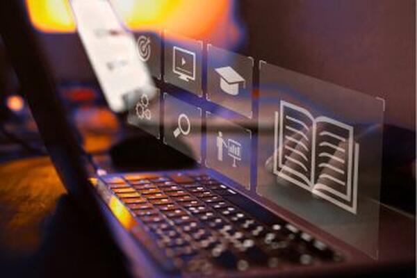 Keyboard with holographic images of book, graduation cap, magnifying glass