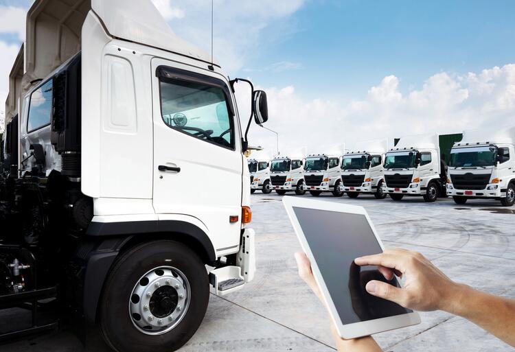 A row of trucks ready for deployment. A hand in the foreground is pointing at a tablet screen.