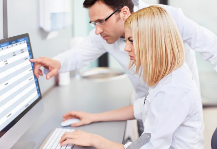 Stock photot of lab techs looking at screen together