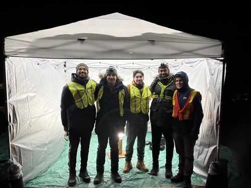 Stratotegic team under a tent canopy at night