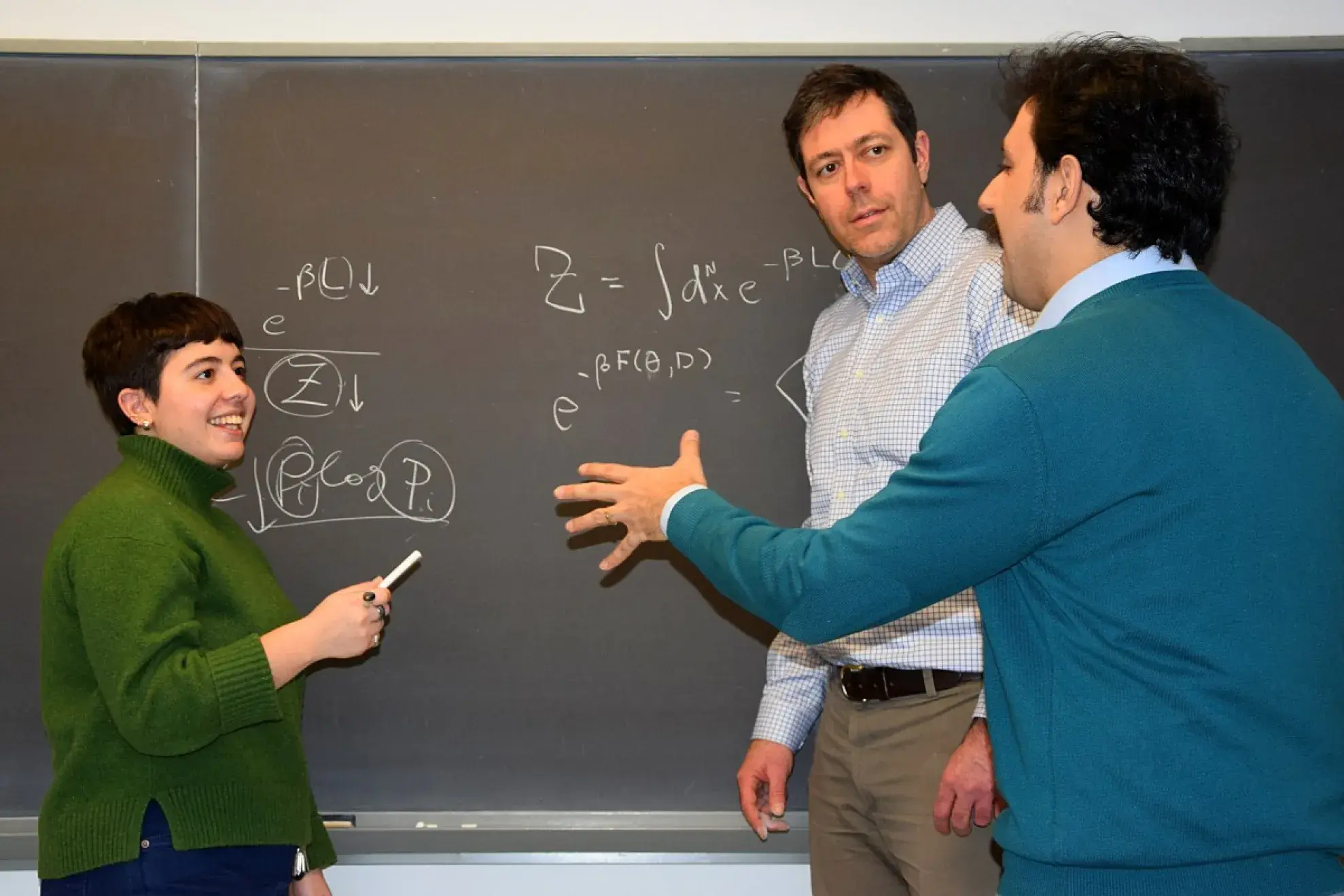 Irina Babayan, Greg van Anders, and Hazhir Aliahmadi discussing physics at a blackboard