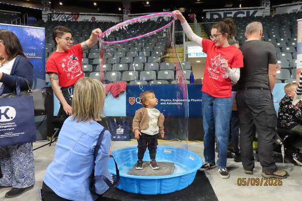 A young visitor experiences standing inside a giant soap bubble.