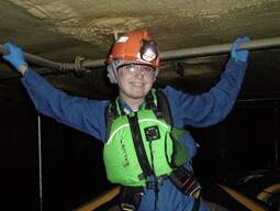 inside the SNO+ cavern. Boats are used to navigate since the cavern is filled with water. In the background one of the detector hold up ropes is visible. 