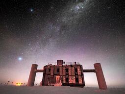 Front view of the IceCube Lab at twilight, with a starry sky showing a glimpse of the Milky Way overhead and sunlight lingering on the horizon. [Credit: Martin Wolf, IceCube/NSF]