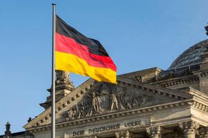 photograph of the German flag in front of the facade of the German parliament building