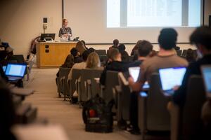 View down an aisle in a lecture theatre to professor at desk in front
