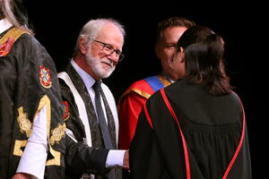 Principal Deane shaking a graduate's hand