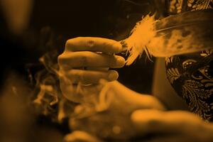 person holding a feather over smoke
