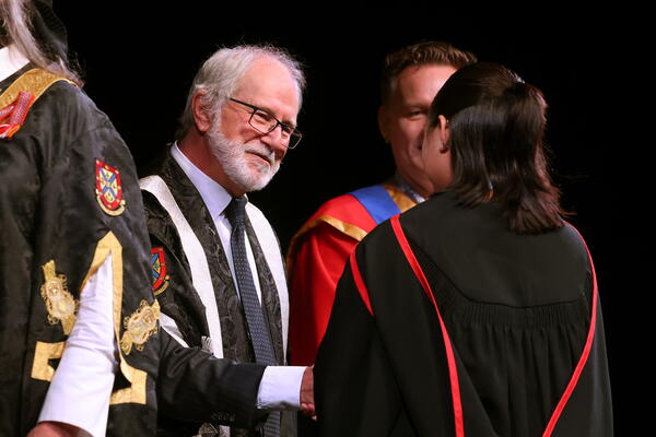 Principal Deane shaking a graduate's hand