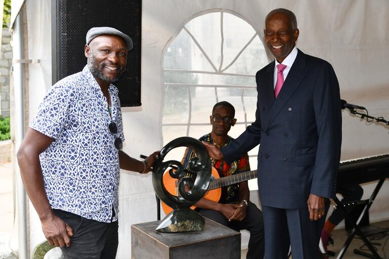 Two men standing next to stone sculpture