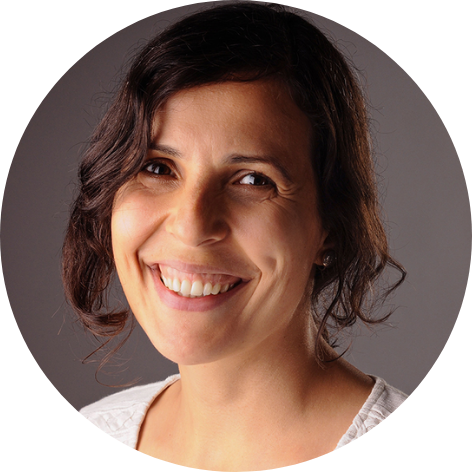 Woman with wavy brown hair in an updo, wearing a white blouse, smiling at the camera.