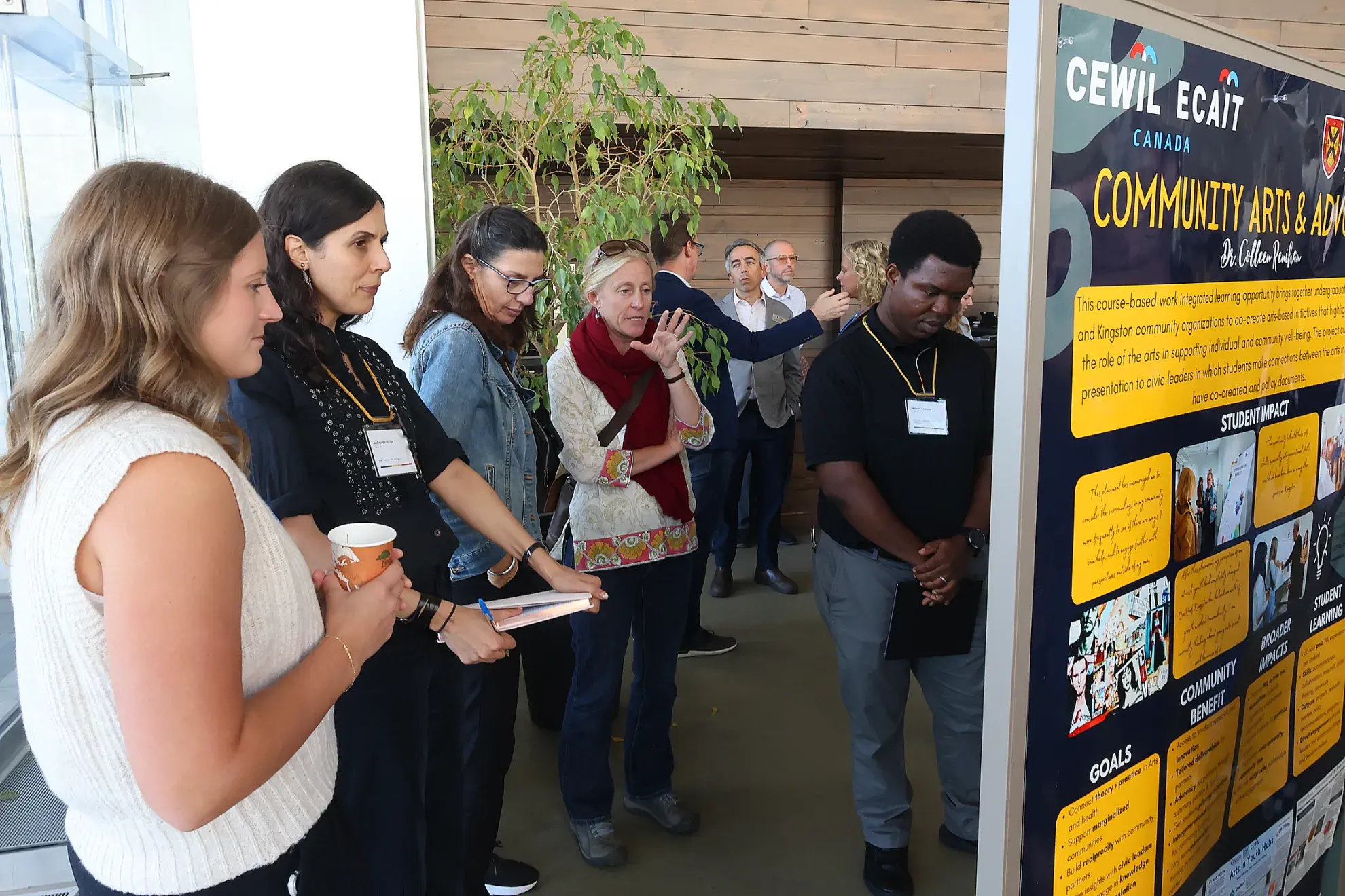 A side view of four women and one man looking at a presentation board.