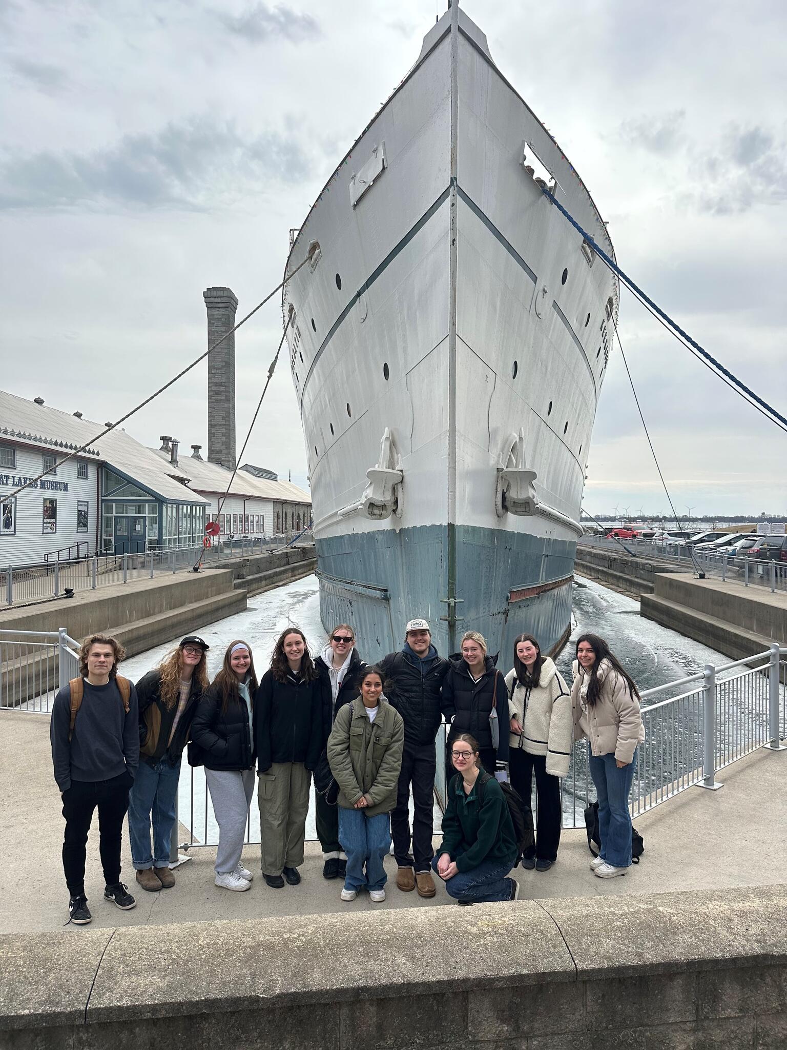 Students standing in front of a tall boat