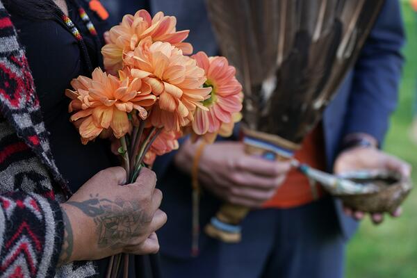 hands holding flowers and hangs holding a feather
