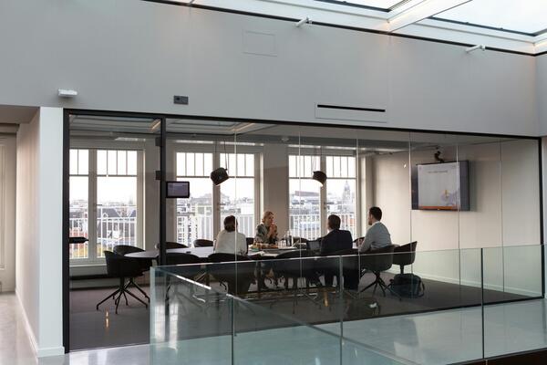 Meeting room with people sitting around a table in office building environment
