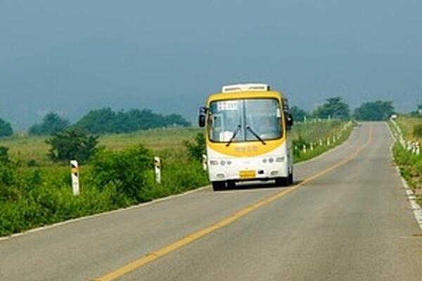 yellow bus driving down a country road
