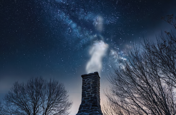 Looking up at a chimney with smoke bellowing out of it. Bare trees n each side signifying winter. The stars are showing with some Norther Light.