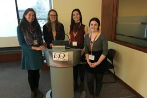 Four people sitting behind a podium with an I@Q sign