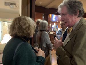 A person talking to someone holding a drink